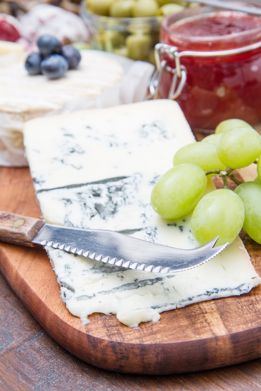 wooden cutting board with cheese, cold cuts and jams